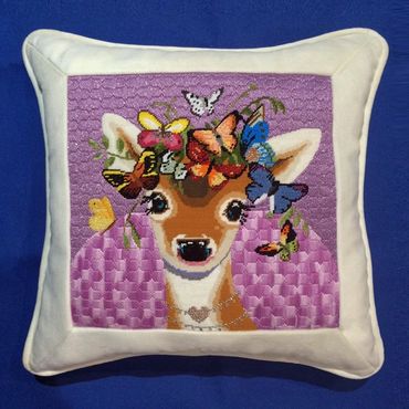 needlepoint pillow finished with the canvas inset into fabric frame, trimmed with self welt cord.
