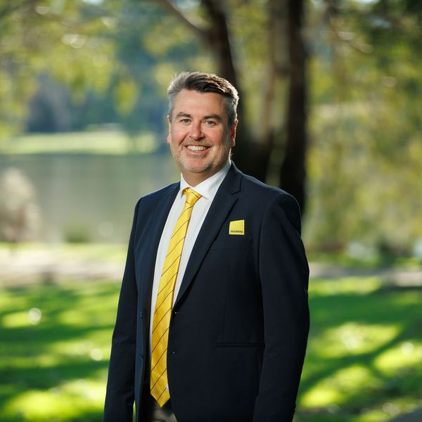 Man in a suit with a yellow tie outdoors.