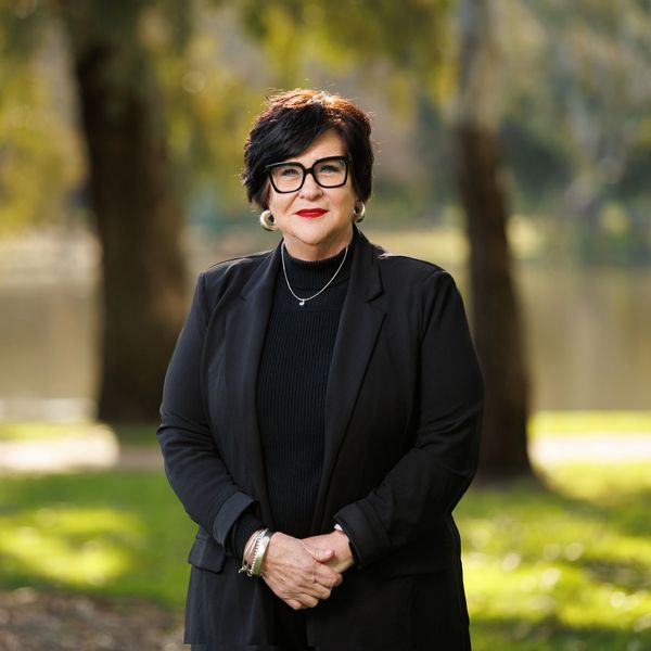 Confident woman in black attire with glasses outdoors.