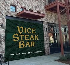 Exterior of Vice Steak Bar with large sign on brick wall.