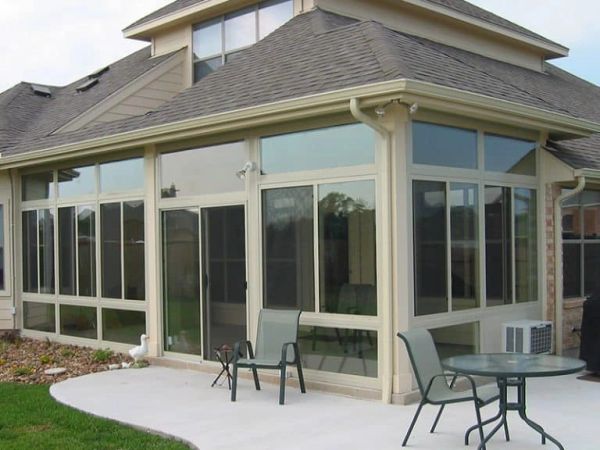 Modern sunroom with large glass windows and patio furniture.