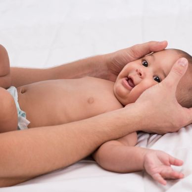 Baby being gently held by adult hands.