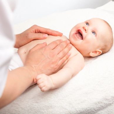 Baby smiling while getting a gentle chest massage.