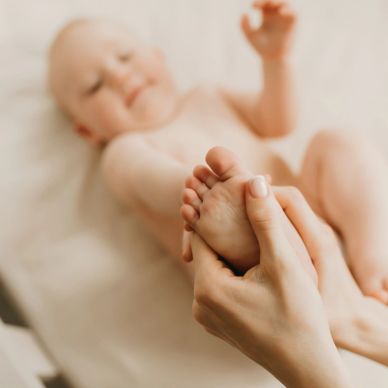 Adult hands gently holding a baby's foot.