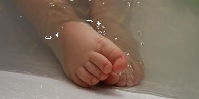 Close-up of a baby's feet submerged in water.