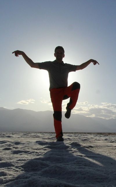 Silhouette of a person balancing on one leg with arms extended.