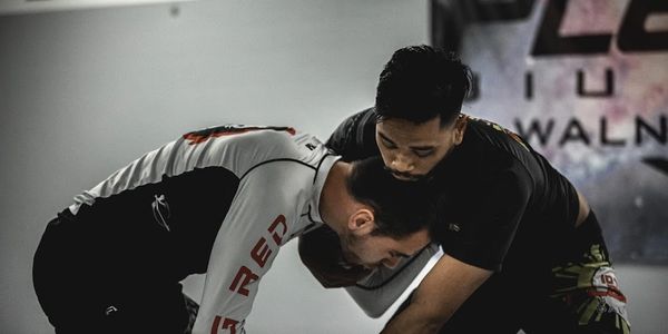 Two men practicing grappling techniques in a martial arts setting.