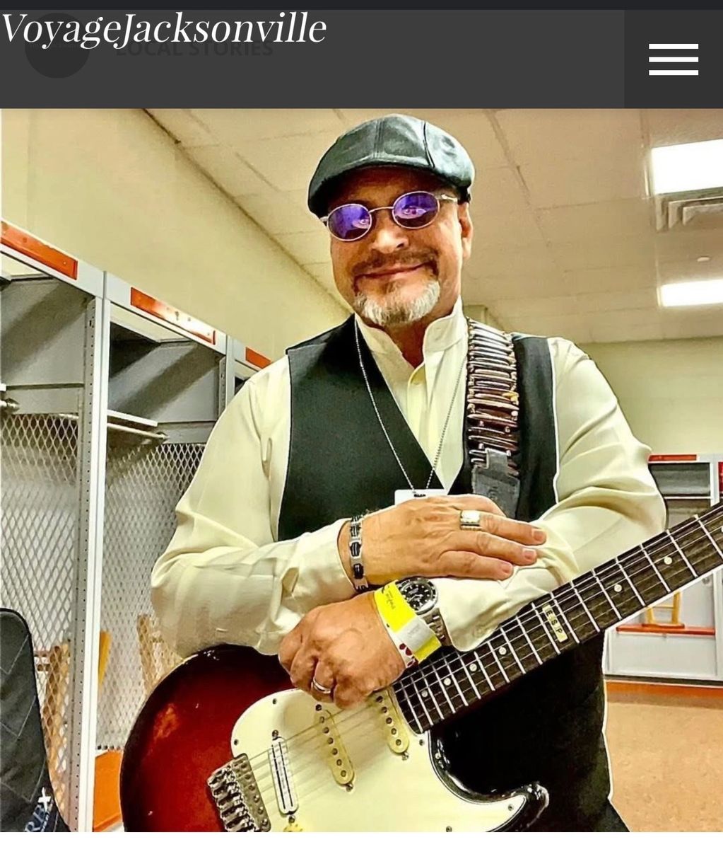 Smiling man with a guitar in a locker room.
