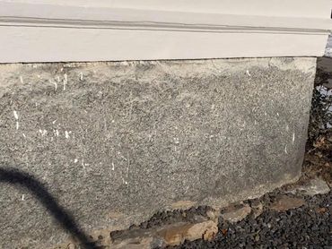 Close-up of a textured stone wall with a white painted upper section.