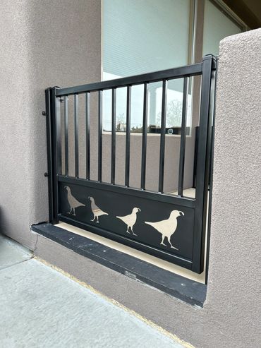 Black metal gate with bird silhouettes on a concrete porch.