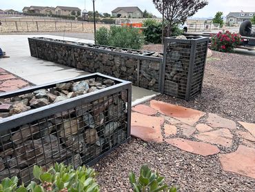Rock-filled metal cages used as garden retaining walls and decorative features.