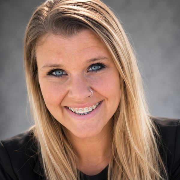 Smiling woman with braces and nose ring.