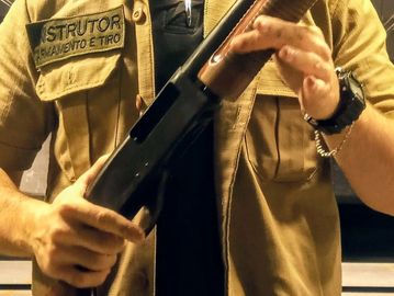 Person handling a shotgun, wearing a shirt labeled 'INSTRUTOR'