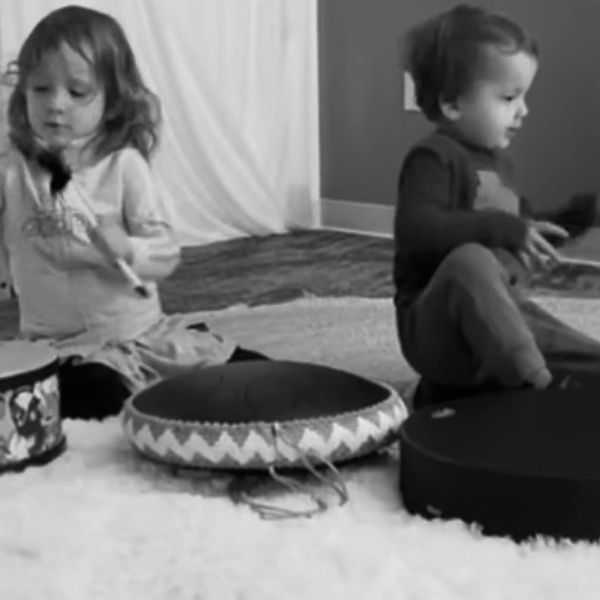 Two kids playing drums indoors.
