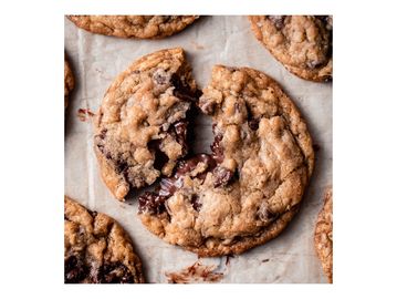 Freshly baked chocolate chip cookies on parchment paper.