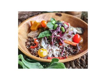 Colorful quinoa salad with fresh vegetables and creamy dressing in a wooden bowl.