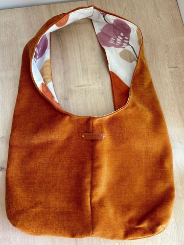 Handmade orange fabric bag with floral inner lining.