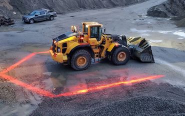 A red FHOSS Halo Exclusion safety lighting system surrounds a heavy excavator.