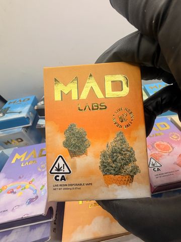 Hand holding a MAD LABS live resin disposable vape package with cannabis imagery.