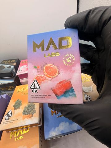 Hand holding MAD Labs live resin vape packaging with colorful design.