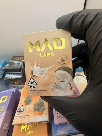 Gloved hand holding a Mad Labs cannabis vape cartridge package.