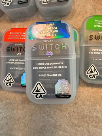 Three colorful Switch liquid live diamond cannabis packages on a beige surface.