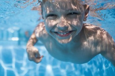 Boy smiling underwater in a pool.