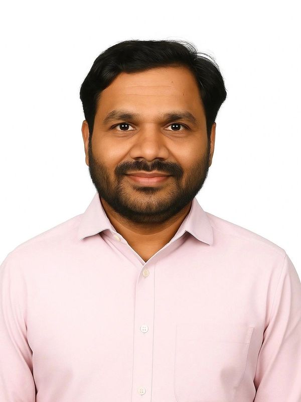Man smiling in a light pink shirt against a white background.
