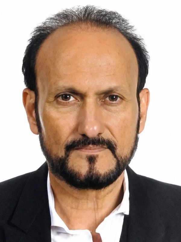 Serious middle-aged man with black beard and suit.