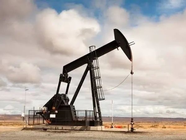 Oil pumpjack under cloudy sky in a barren landscape.