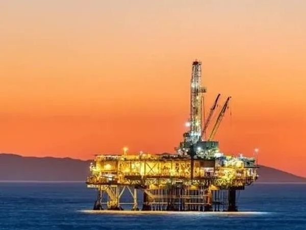 Illuminated offshore oil rig at sunset.