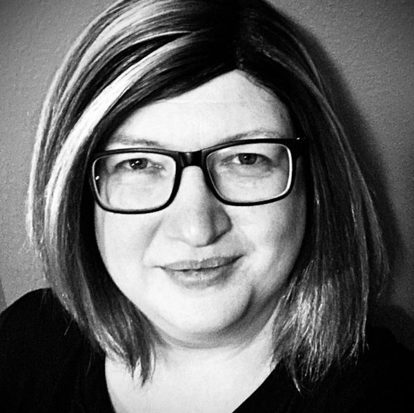 Black and white portrait of a woman with glasses and shoulder-length hair.