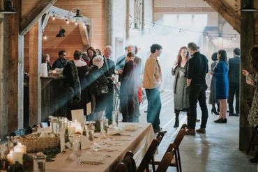 People socializing in a warmly lit rustic wooden venue with a decorated dining table.