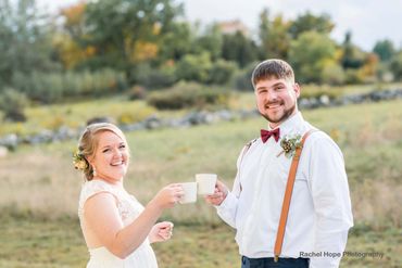 Happy couple toasting with mugs outdoors at their wedding.