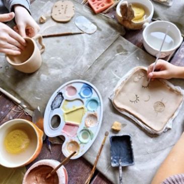 People painting pottery at a crafting table.