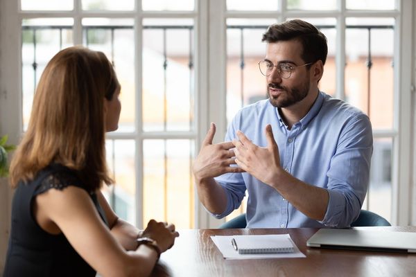 Man explaining something to a woman in a meeting.
