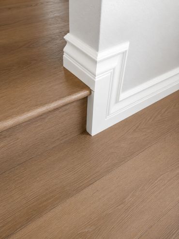 Elegant wooden staircase with white decorative baseboard molding.