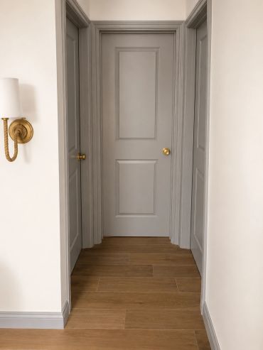 Hallway with three closed gray doors and wooden flooring.