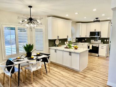 Modern kitchen with white cabinets, a marble island, and a stylish dining area.