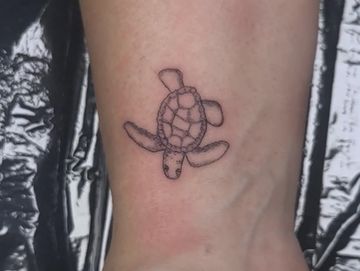 Simple black line tattoo of a sea turtle on skin.