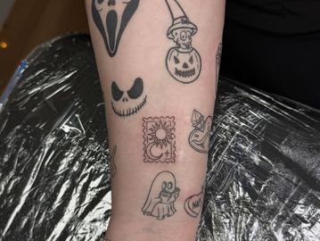 Forearm tattoo sleeve featuring Halloween-themed designs in black ink.