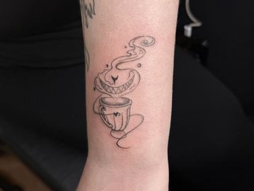A whimsical tattoo of a grinning coffee cup with steam on a forearm.