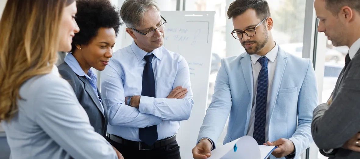 Five business professionals reviewing documents during a meeting.
