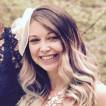 young woman smiling with blonde/brown hair wearing a small hat and a pretty pink dress