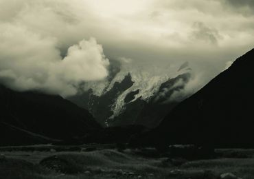 Moody mountain landscape with clouds and glacier.