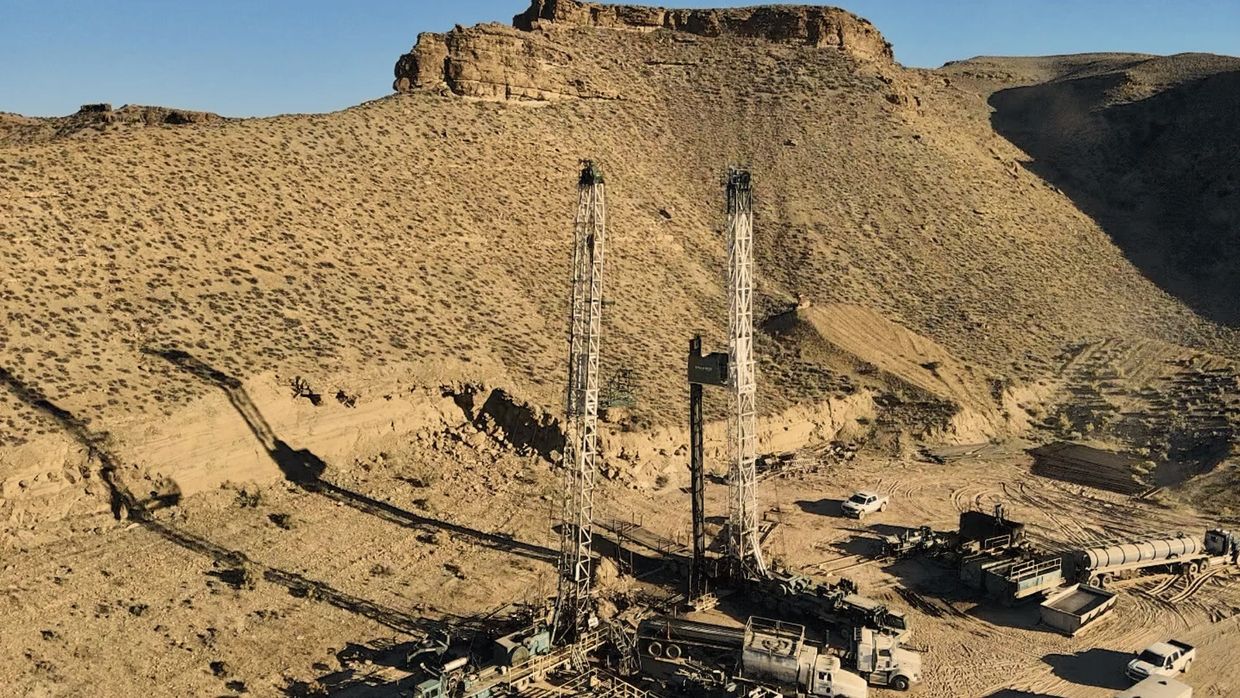 workover rig and service trucks in desert oilfield