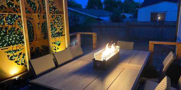 Backyard deck features a lighted tree of life and gas fire pit table. 