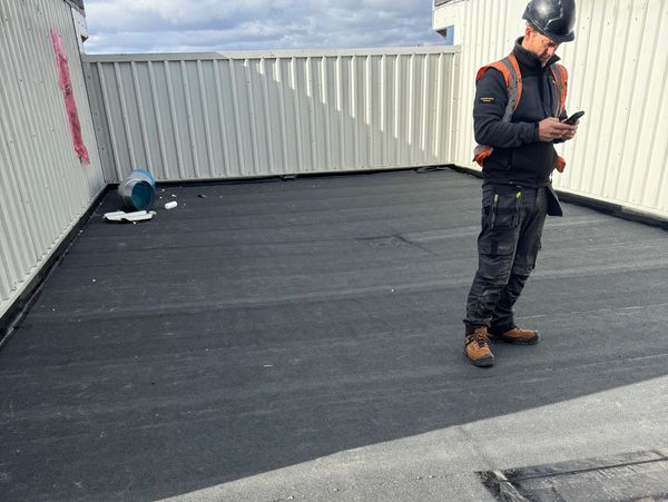 Roofer inspecting flat roof project.