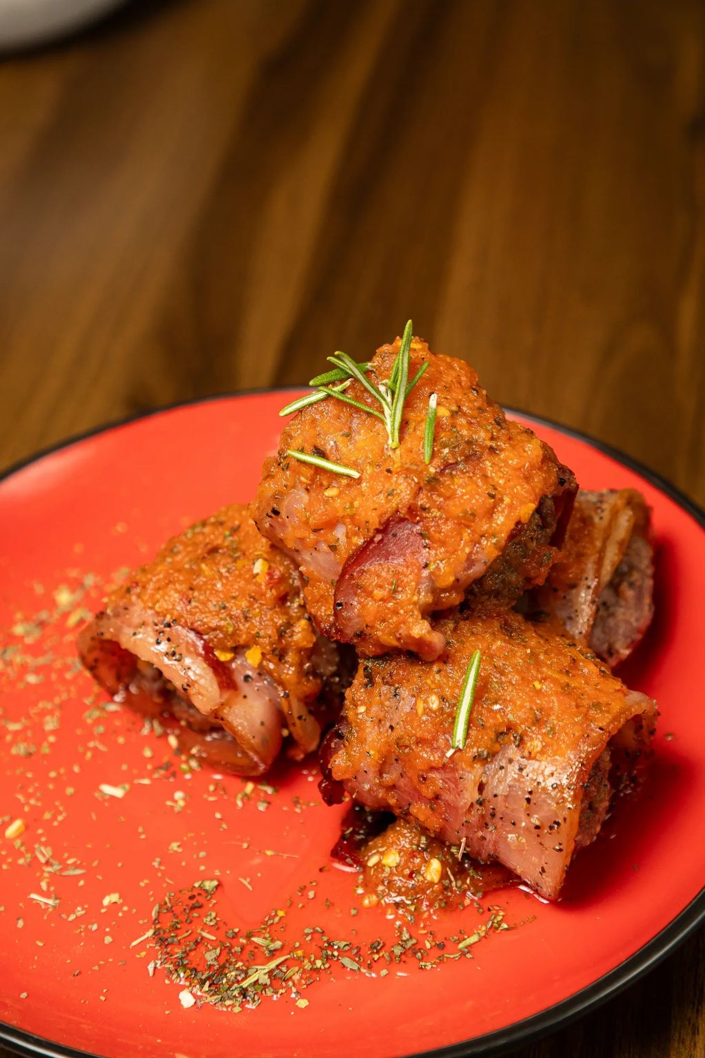 Romula Meatballs, albondigas envueltas en tocino caramelizado, bañadas en salsa de tomate.