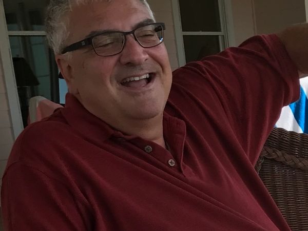 Man in glasses laughing joyfully wearing a red shirt.